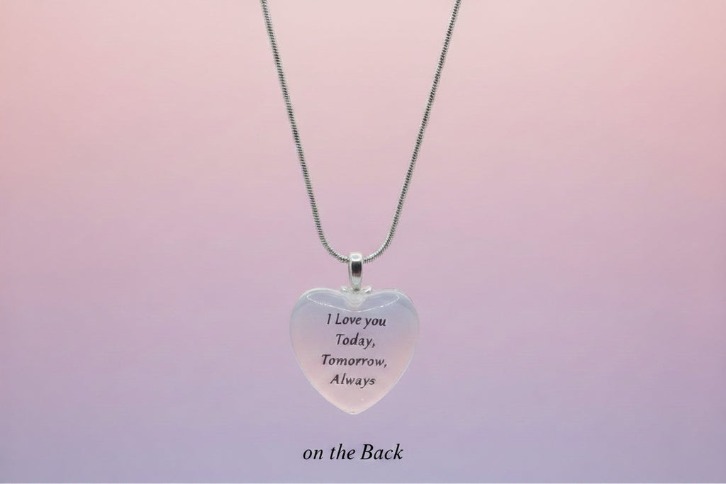 Heart-shaped pendant with engraved text on a light gray background