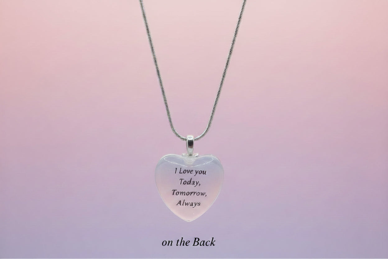 Heart-shaped pendant with engraved text on a light gray background