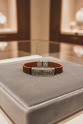 Brown leather bracelet with metal 'believe' tag on a blue cushion