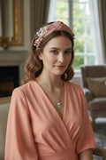 Necklace on a card with 'AMOR' text, next to a pink clutch and flowers on a decorative background