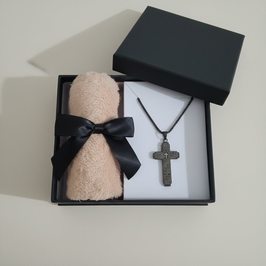 Men's Black Necklace with cross pendant The lords prayer on it, a cardboard backing,  a face towel wrapped with a black ribbon, against a white background